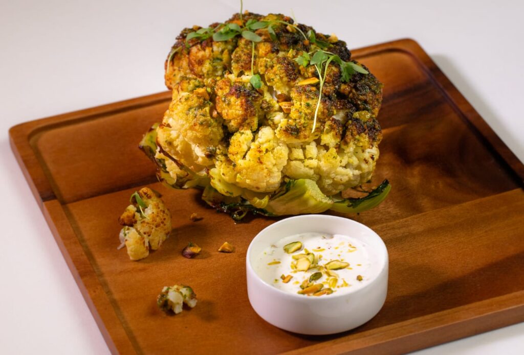 Whole roasted cauliflower with pistachio crumble and green onion creme fraiche